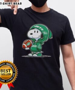 Alt Text: Snoopy wearing a New York Jets hoodie smiles at fans on a fun Peanuts-themed t-shirt design.