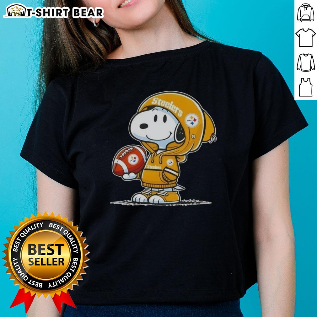 Official Peanuts Snoopy Wearing Hoodie Pittsburgh Steelers And Smilling At Fans Ladies-Tee Snoopy wearing a Pittsburgh Steelers hoodie smiles at fans on a ladies tee, showcasing official Peanuts merchandise.