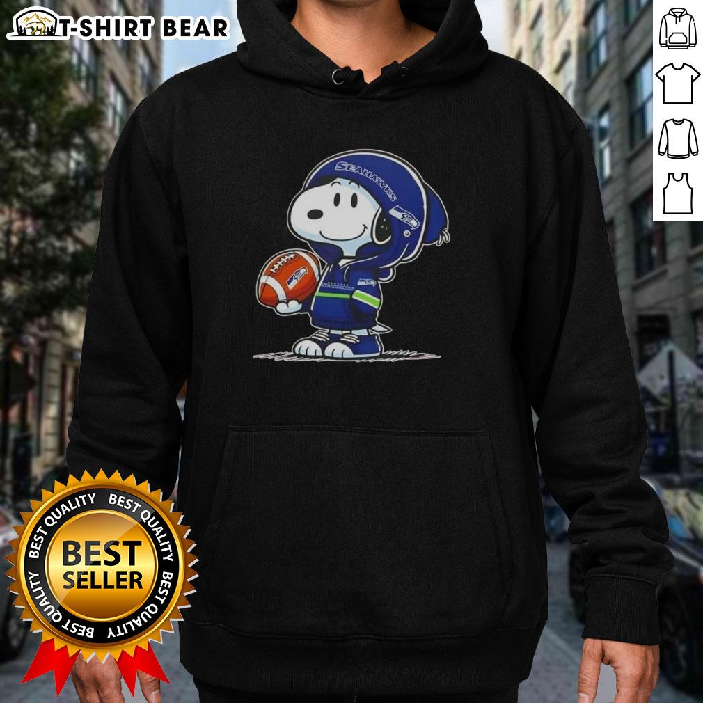 Official Peanuts Snoopy Wearing Hoodie Seattle Seahawks And Smilling At Fans Hoodie Snoopy wearing a Seattle Seahawks hoodie smiles at fans in this official Peanuts image, showcasing team spirit and fun.