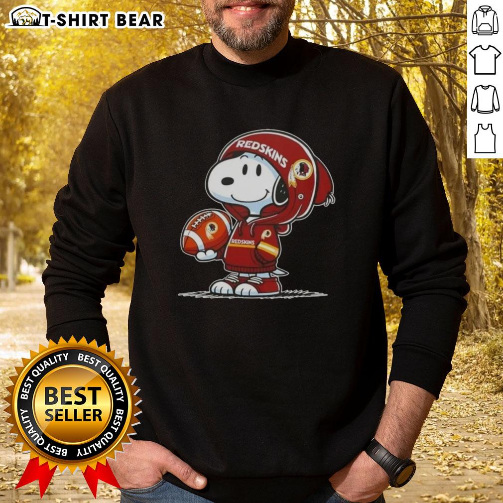 Official Peanuts Snoopy Wearing Hoodie Washington Commanders And Smilling At Fans Sweatshirt Alt Text: Snoopy in a Washington Commanders hoodie smiles at fans, showcasing the official Peanuts sweatshirt design.