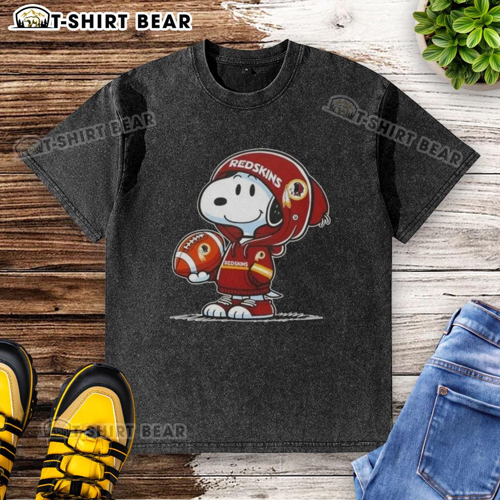 Official Peanuts Snoopy Wearing Hoodie Washington Commanders And Smilling At Fans Washed T-Shirt Alt Text: Snoopy in a Washington Commanders hoodie, smiling at fans, featured on a washed t-shirt design. Official Peanuts merchandise.