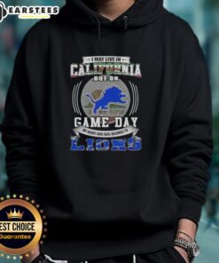 Detroit Lions football hoodie with 'I May Live in California But On Game Day' slogan, perfect for fans and game day attire.
