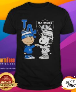 Awesome Charlie Brown fist bump with Snoopy on a Dodgers X Raiders T-shirt, perfect for Los Angeles sports fans.