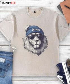 Detroit Lions mascot in a beanie and sunglasses, showcasing a stylish washed t-shirt at a football event.