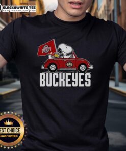 Alt Text: Snoopy and Woodstock joyfully driving a car, wearing an Ohio State Buckeyes flag t-shirt, showcasing a fun team spirit.