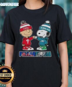 Adorable Charlie Brown and Snoopy fist bump on a Philadelphia sports tee, celebrating Phillies and Eagles pride.