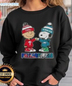 Adorable Charlie Brown and Snoopy fist bump in Philadelphia City Sports sweatshirt featuring Phillies and Eagles logos.