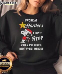 Funny Snoopy sweatshirt featuring 'I work at Hardee's, I don't stop when I'm tired, I stop when I'm done' Christmas design.