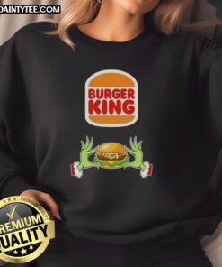 Good Grinch hands holding a festive Burger King sweatshirt, perfect for a Merry Christmas celebration.