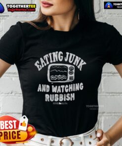 Happy woman enjoying junk food and watching TV at home, wearing a Home Alone themed ladies tee for comfort and fun.