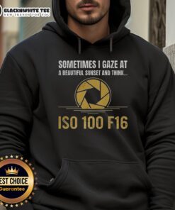 Alt Text: Happy person wearing an 'Iso 100 F16' hoodie, gazing at a stunning sunset with vibrant colors.