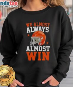 Happy football fan wearing 'We Almost Always Almost Win' sweatshirt, showcasing team spirit and humor at the game.