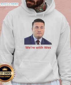 Happy Wes wearing a 'We're With Wes' hoodie, smiling outdoors, showcasing vibrant colors and a cheerful vibe.