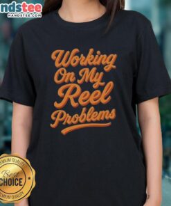 Happy woman wearing 'Working On My Reel Problems' fishing ladies tee, enjoying a day out on the water with her fishing gear.