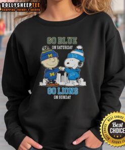 Charlie Brown and Snoopy fist bump in 'Go Blue' sweatshirt, cheering for Detroit Lions. Perfect fan gear for game day!