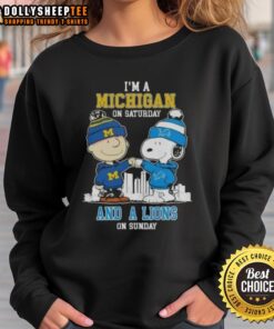 Charlie Brown and Snoopy fist bump in 'I'm a Michigan on Saturday and a Detroit Lions on Sunday' skyline sweatshirt.