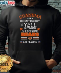 Cheerful grandma in Chicago Bears hoodie, passionately reacting while watching a football game, showcasing her team spirit.