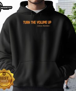 Zohran Mamdani wearing a stylish 'Turn the Volume Up' hoodie, promoting community engagement as Mayor.