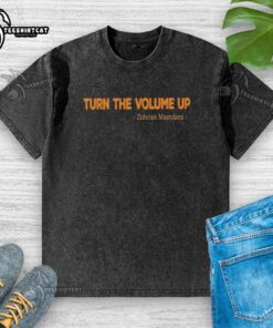 Zohran Mamdani mayor wearing a washed t-shirt with 'Turn The Volume Up' slogan, promoting community engagement.