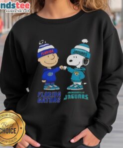 Official Charlie Brown fist bump with Snoopy on Florida Gators x Jacksonville Jaguars sweatshirt, perfect for fans.