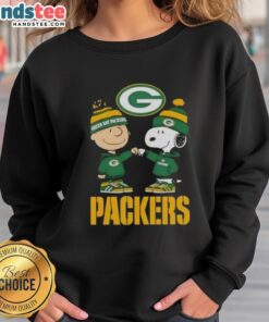 Official Charlie Brown fist bump with Snoopy on a Green Bay Packers sweatshirt, perfect for fans and cozy wear.