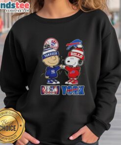 Official Charlie Brown fist bump with Snoopy, NYC skyline, featuring Yankees and Buffalo Bills on a stylish sweatshirt.