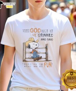 Alt Text: Official Peanuts Snoopy Cowboy t-shirt with 'When God Made Me He Grinned And Said This'll Be Fun' slogan.
