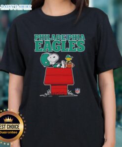 Alt Text: Official Philadelphia Eagles Snoopy relaxing with a football in Peanuts style on a ladies tee, perfect for fans.