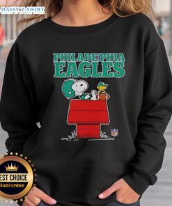 Official Philadelphia Eagles Snoopy sweatshirt featuring Snoopy chilling with a football in Peanuts style.