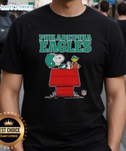 Alt Text: Official Philadelphia Eagles Snoopy T-shirt featuring Peanuts style design with Snoopy chilling and holding a football.