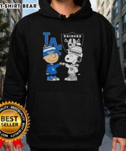 Alt Text: Original Charlie Brown fist bump with Snoopy in Los Angeles sports hoodie featuring Dodgers and Raiders logos.