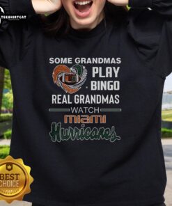 Premium sweatshirt featuring grandmas playing bingo while watching Miami Hurricanes game, perfect for sports fans.