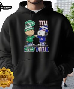 Pretty Charlie Brown fist bump with Snoopy in New York City, wearing Jets x Giants hoodie, celebrating sports spirit.