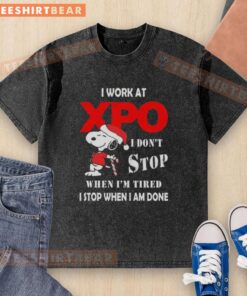 Alt Text: Cute Snoopy graphic on a Christmas-themed washed t-shirt, featuring 'I work at XPO, I don't stop when I'm tired.'