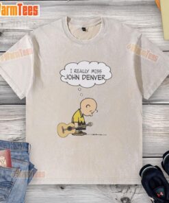 Charlie Brown holding a guitar in a 'I Really Miss John Denver' washed t-shirt, evoking nostalgia and musical tribute.