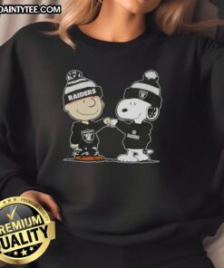 Cute Peanuts Charlie Brown and Snoopy fist bump in Las Vegas Raiders football sweatshirt, perfect for fans.