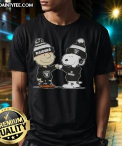 Charlie Brown and Snoopy fist bump on a football T-shirt, celebrating Peanuts with Las Vegas Raiders theme.