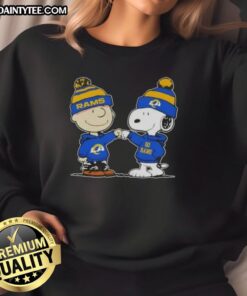 Cute Peanuts Charlie Brown and Snoopy fist bump in Los Angeles Rams football sweatshirt, perfect for fans and cozy wear.