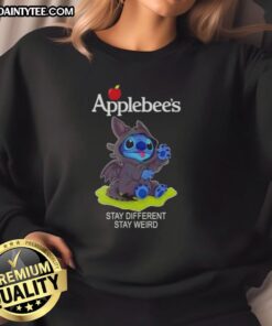 Alt Text: Cute Stitch cosplay wearing a Toothless-themed sweatshirt at Applebee's, promoting Stay Different, Stay Weird message.