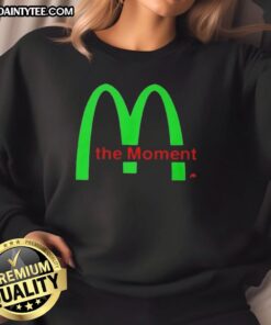 Alt Text: Charli XCX wearing a stylish 'Good Charli XCX The Moment Sweatshirt' in a vibrant urban setting.