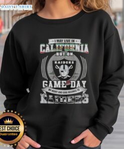 Alt Text: Fan wearing 'Good I May Live In California But My Heart Belongs To Las Vegas Raiders' sweatshirt on game day.