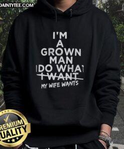 Man wearing 'Good I'm a Grown Man I Do What I Want My Wife Wants' hoodie, showcasing casual style and humor.