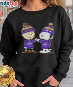 Charlie Brown and Snoopy fist bump in a Baltimore Ravens football sweatshirt, celebrating friendship and team spirit.