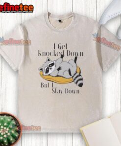 Funny raccoon meme on a washed t-shirt: 'I get knocked down but I stay down' - perfect for humor lovers.
