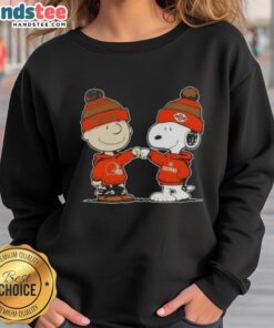 Charlie Brown and Snoopy fist bump in Cleveland Browns sweatshirt, showcasing a fun Nice Peanuts design for football fans.