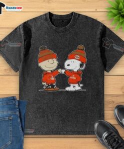 Charlie Brown and Snoopy fist bump in Cleveland Browns football t-shirt, showcasing playful Peanuts fandom.