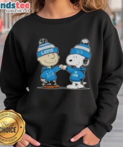 Charlie Brown and Snoopy fist bump on a Detroit Lions football sweatshirt, perfect for Peanuts fans and sports lovers.