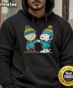 Alt Text: Charlie Brown and Snoopy fist bump in Jacksonville Jaguars hoodie, celebrating friendship and football spirit.