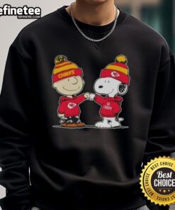 Charlie Brown and Snoopy fist bump in Kansas City Chiefs football sweatshirt; perfect for Peanuts fans and football lovers.