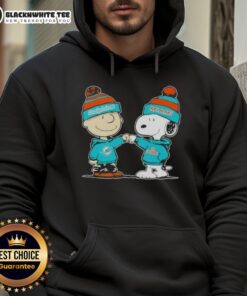 Charlie Brown and Snoopy fist bump in Miami Dolphins football hoodie, showcasing Nice Peanuts style and team spirit.